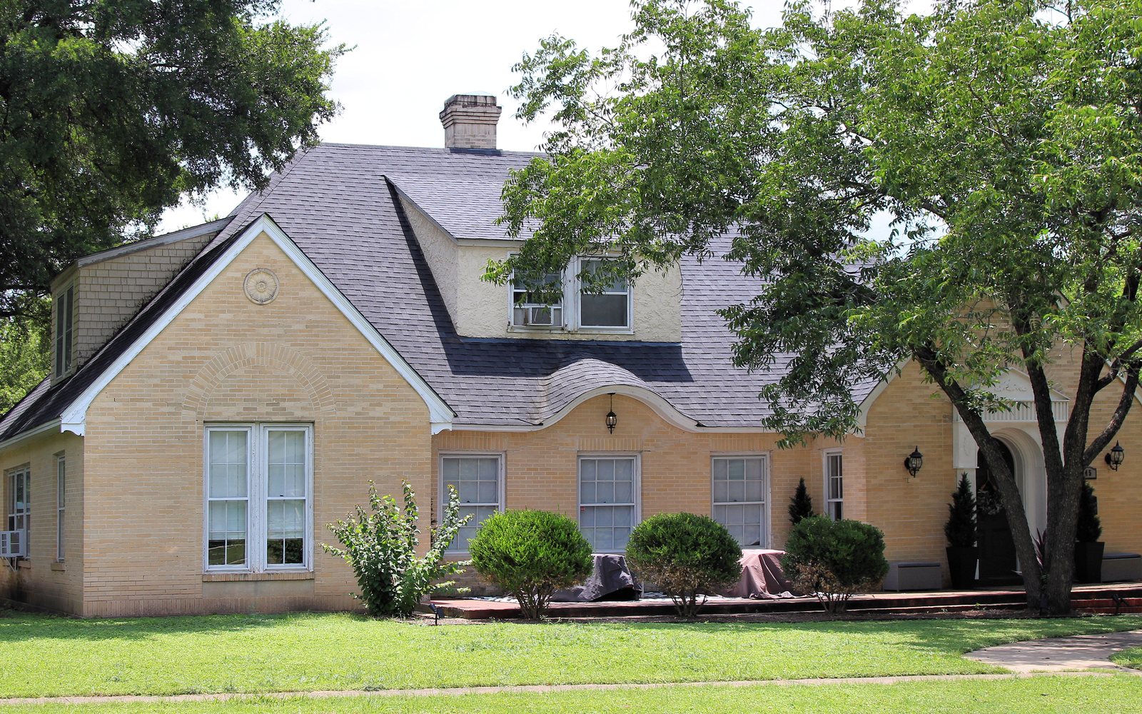 A brick house with a slate roof behind a green lawn in Belton