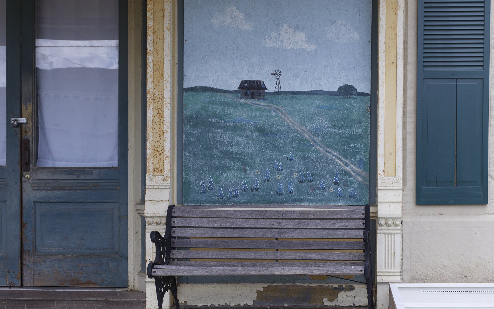 A bench under a painted mural on a storefront in Moody