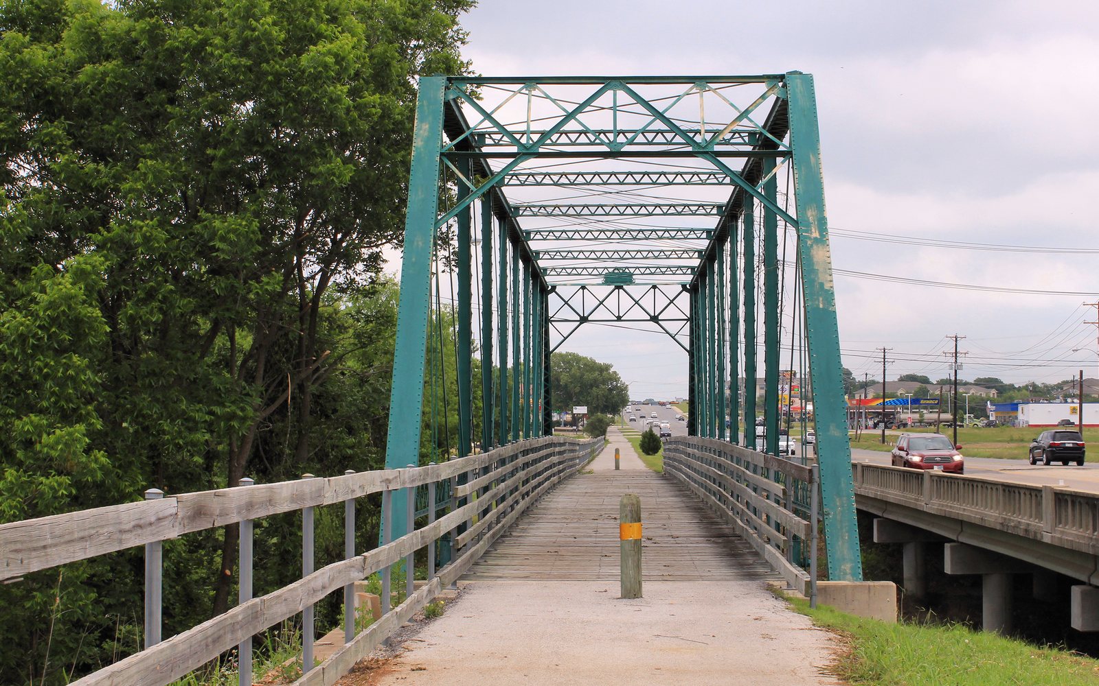 A green truss bridge on a paved trail in Temple