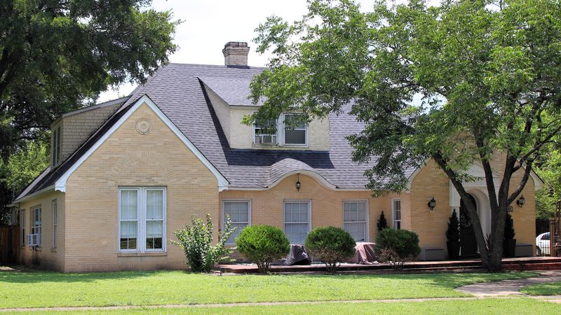 A brick house with a slate roof behind a green lawn in Belton