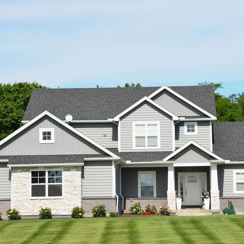 A two-story house behind a mown lawn